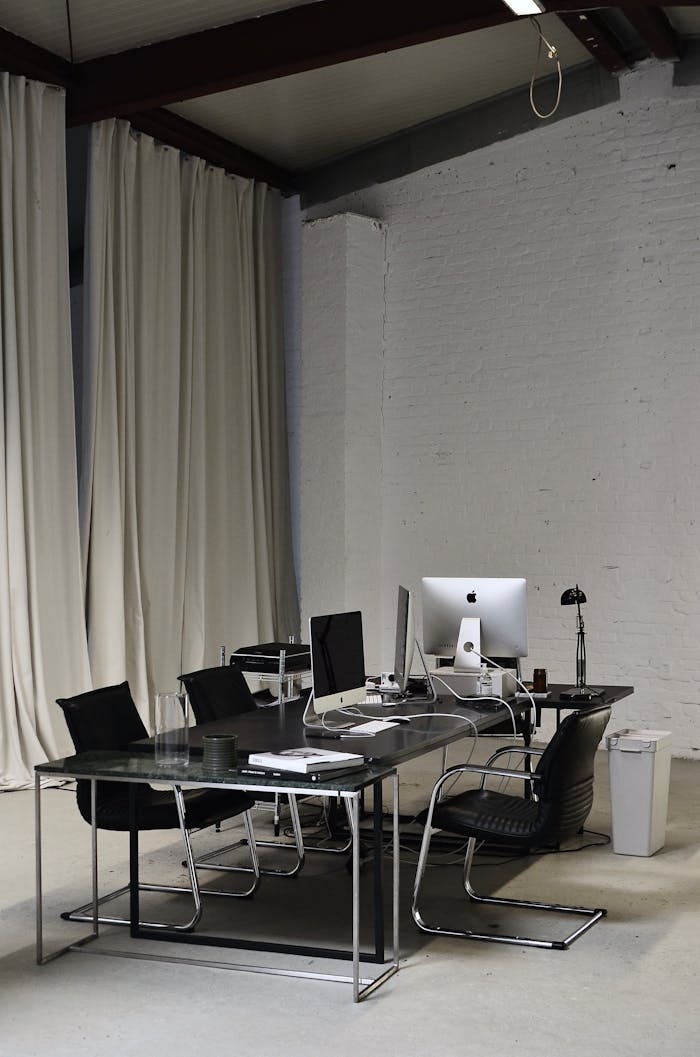 Spacious and contemporary office setup with desks and computers in a minimalist style.